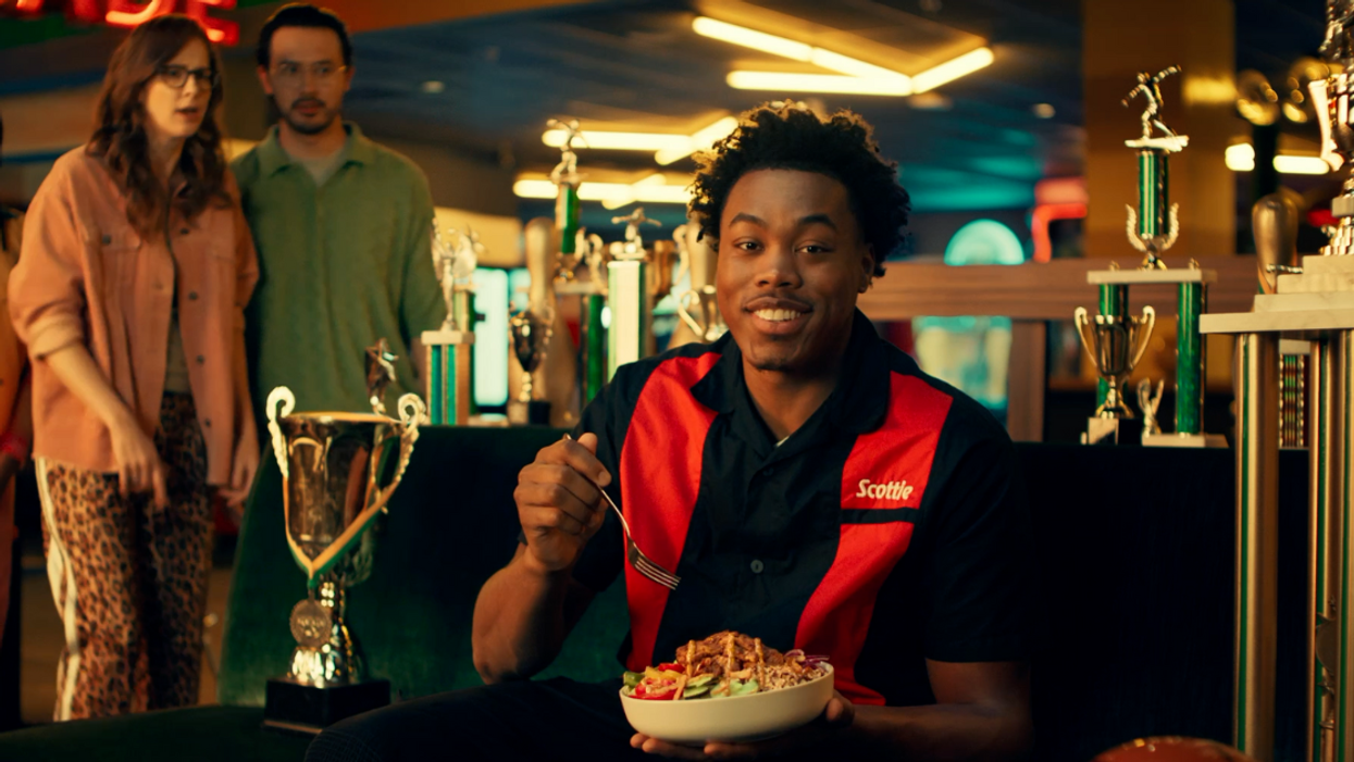 Scottie Barnes sits in front of trophies in a bowling alley holding Subway Canada's Jerk-Spiced Chicken Rice Bowl.