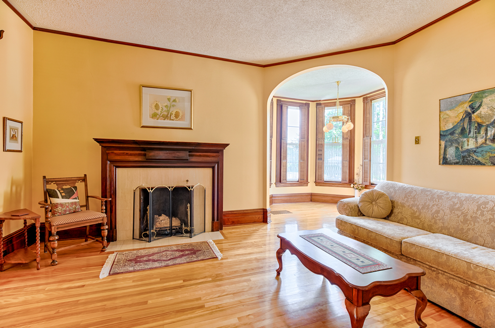 Seating area in the house, with large windows, a fireplace, a floral sofa and hardwood floors.