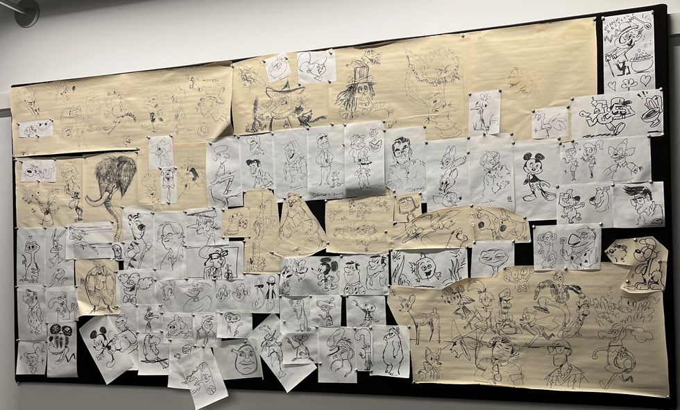 Sketches of various cartoon characters on a corkboard.