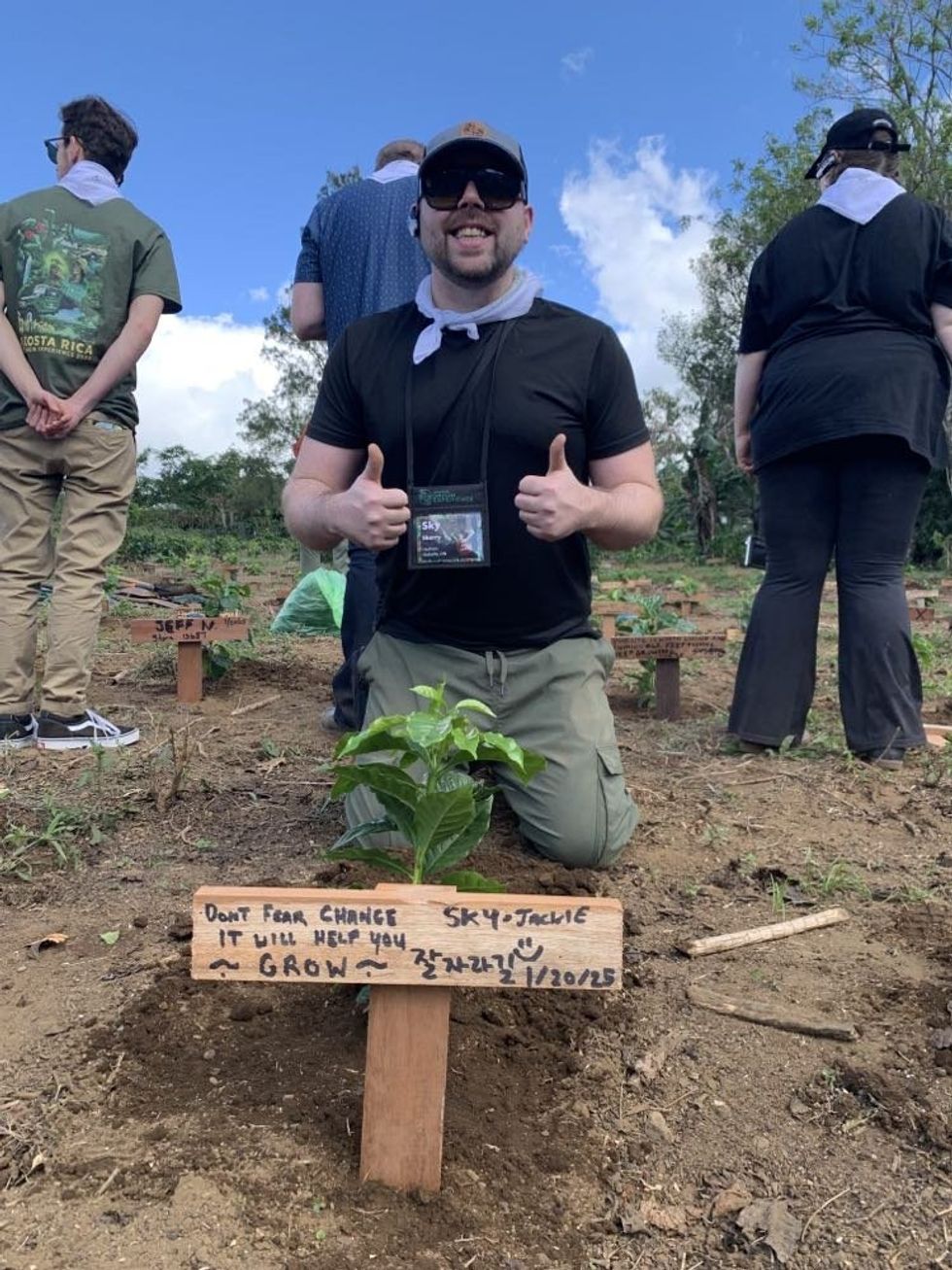 Skyler Skerry poses with the coffee sapling he planted at Hacienda Alsacia.