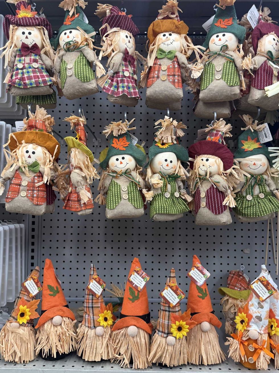 Small scarecrows and gnomes in fall clothes and colours on a store shelf.