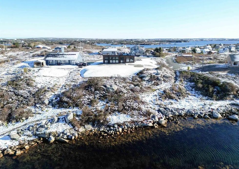 snow-covered house for sale in nova scotia with the ocean in front of it