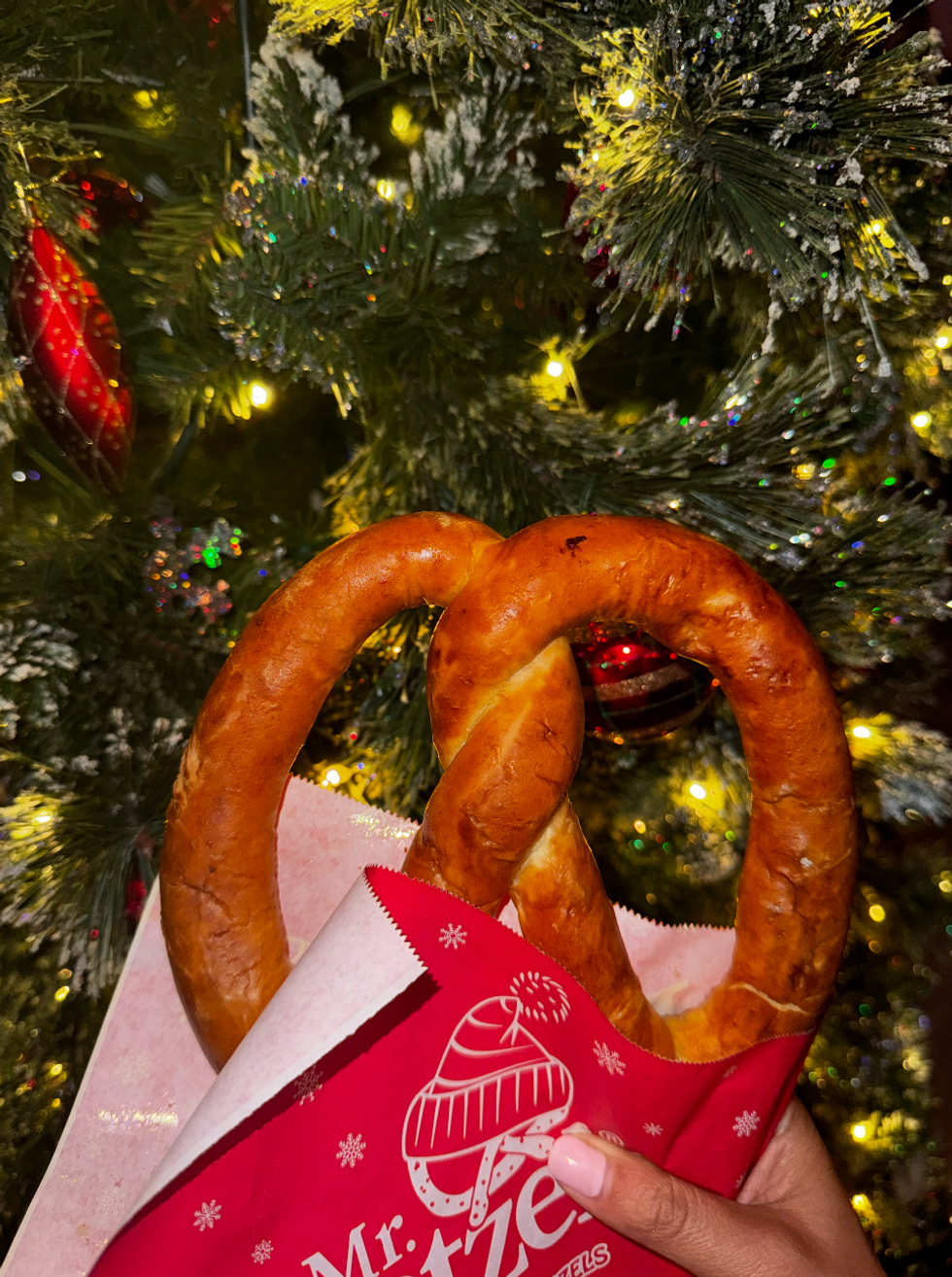 Soft pretzel from Mr.Pretzel with a Christmas tree in the background.