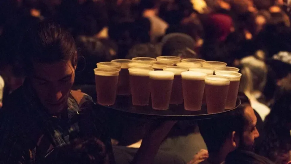 Someone carries a massive tray with cups of beer.
