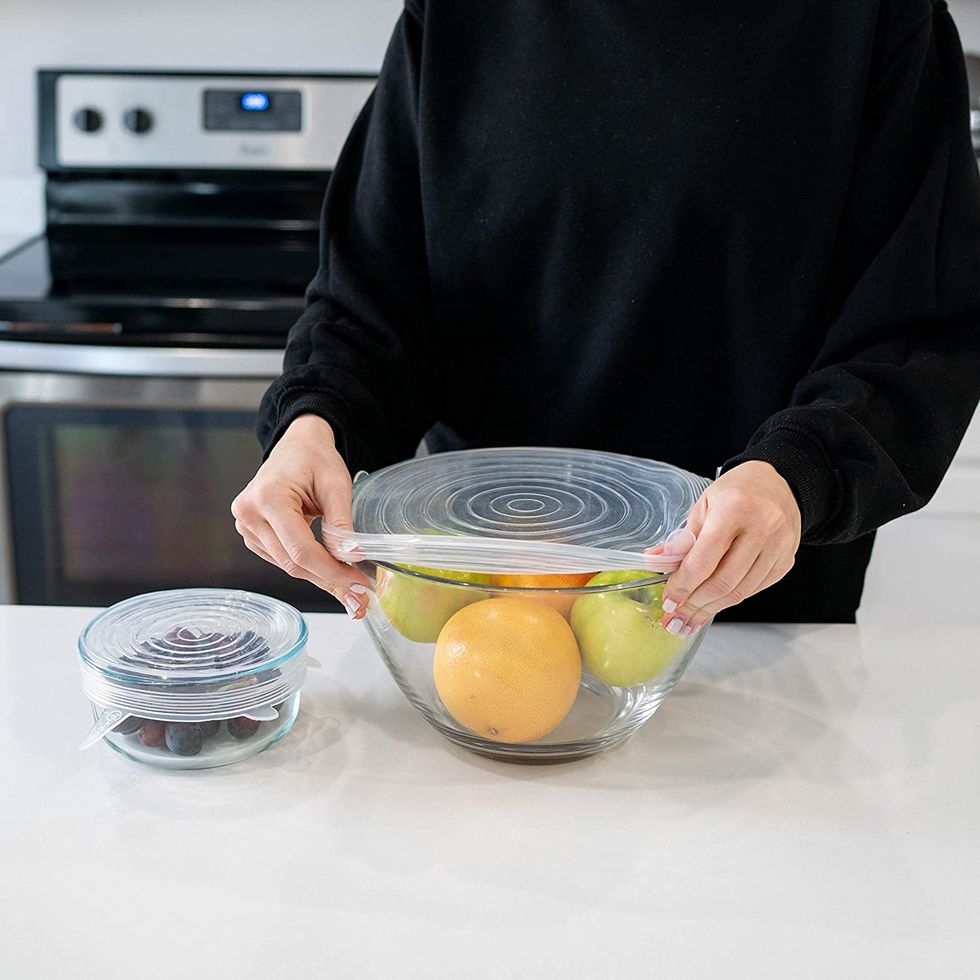 Someone dressed in black closing a bowl with a stretch lid.