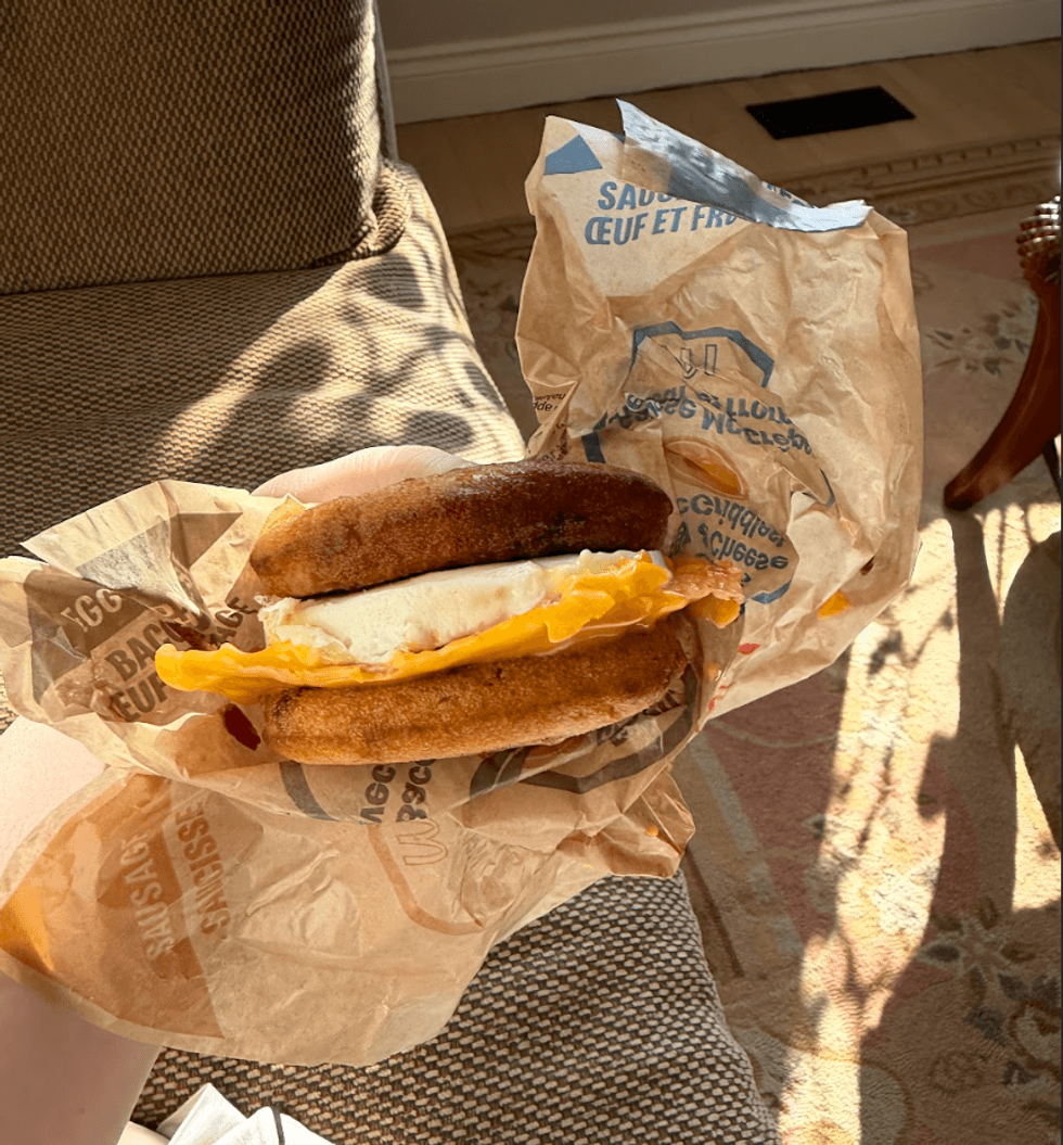 Someone holding a breakfast sandwich.