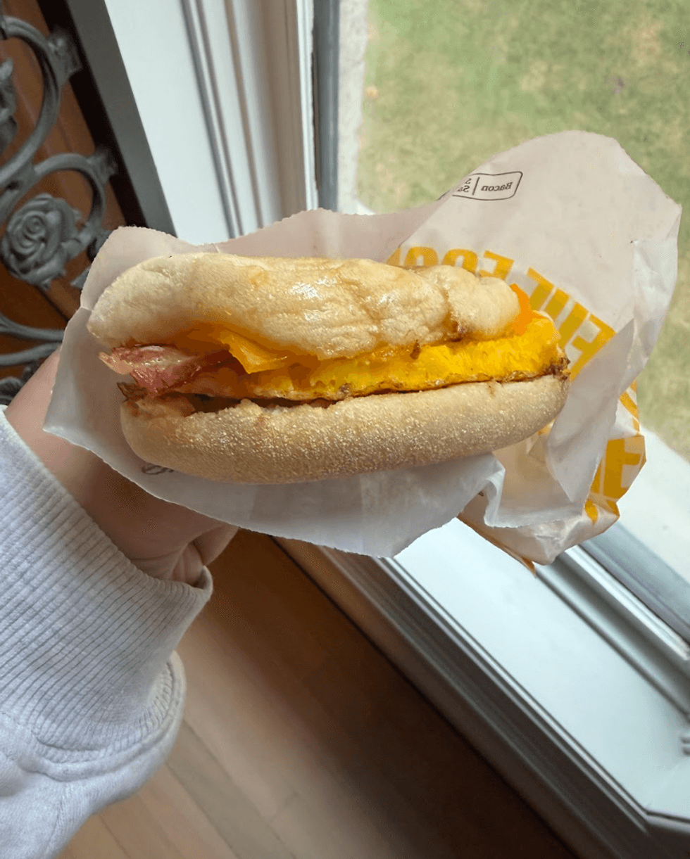 Someone holding a breakfast sandwich.