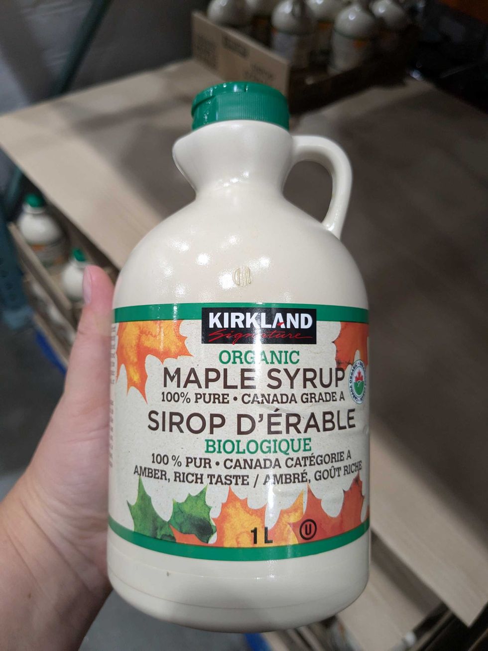 Someone holding a Costco Kirkland jug of maple syrup