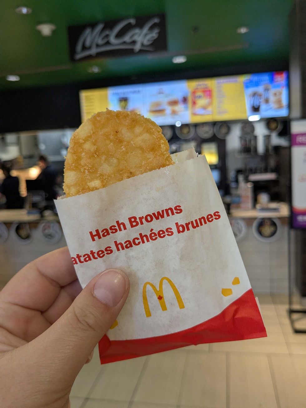 Someone holding a hashbrown from McDonald's up in front of the store