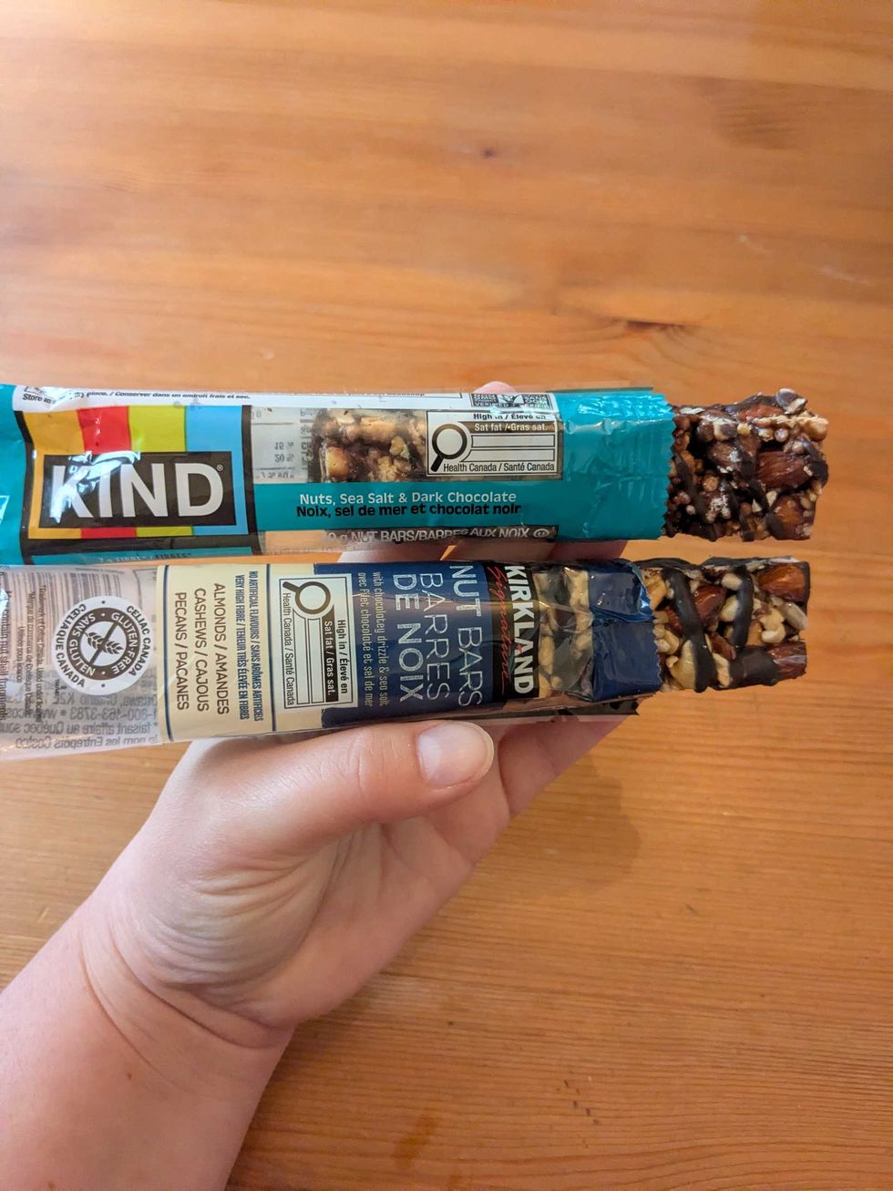 Someone holding a KIND and Kirkland granola bar side by side