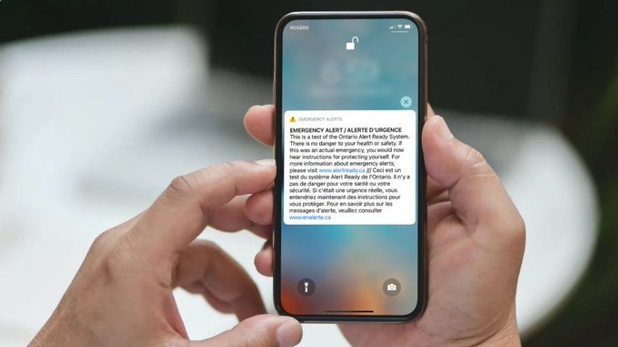 Someone holding a phone with an emergency alert on the screen.