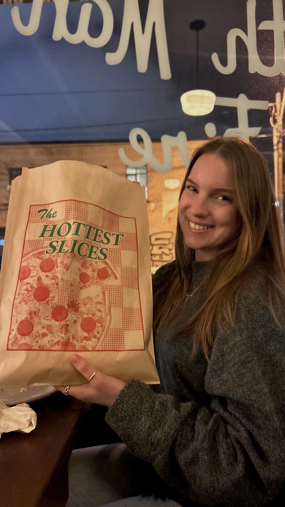 Someone holding a pizza slice in a bag.