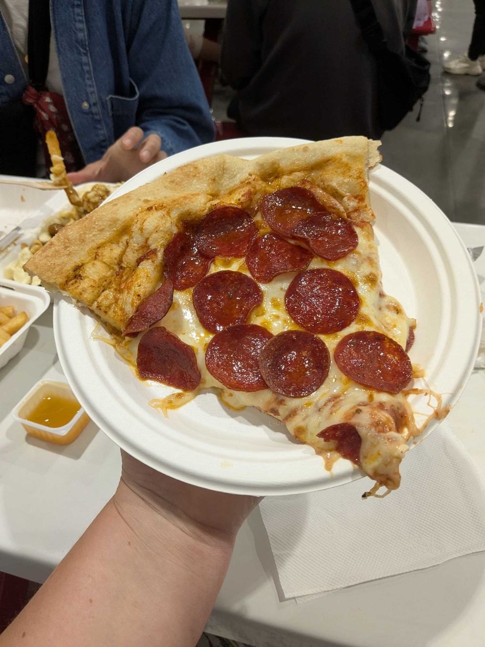 Someone holding a plate with a slice of pepperoni pizza on it