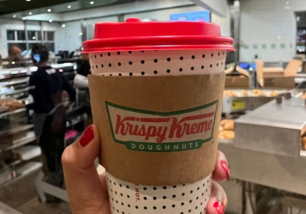 Someone holding a pumpkin spice latte at Krispy Kreme Doughnuts