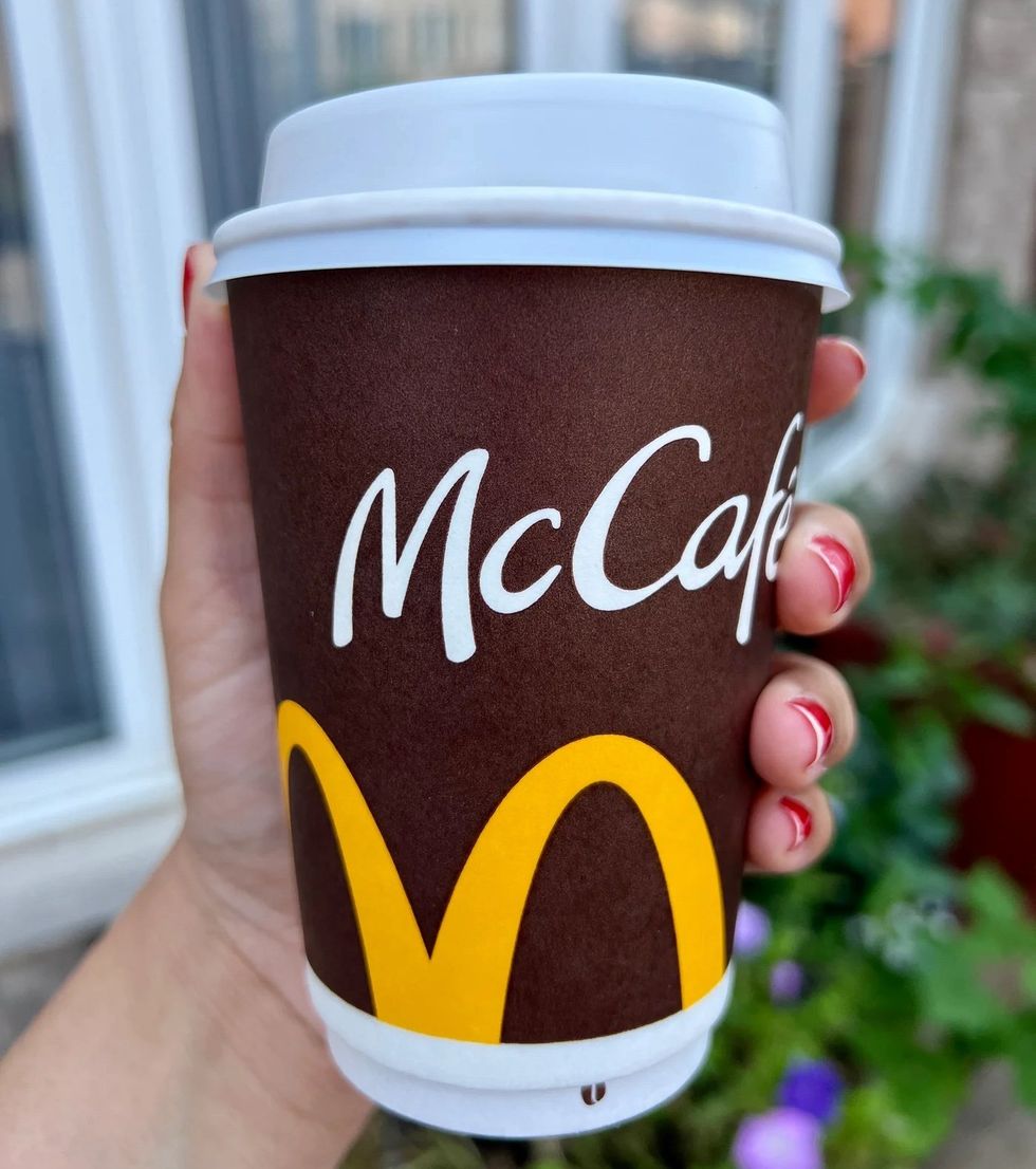 Someone holding a pumpkin spice latte from McDonalds