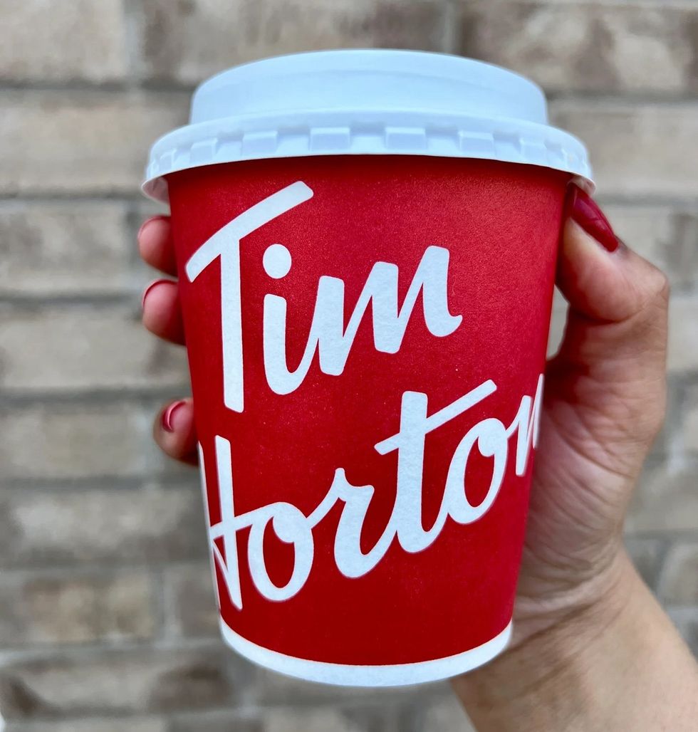 Someone holding a pumpkin spice latte from Tim Hortons