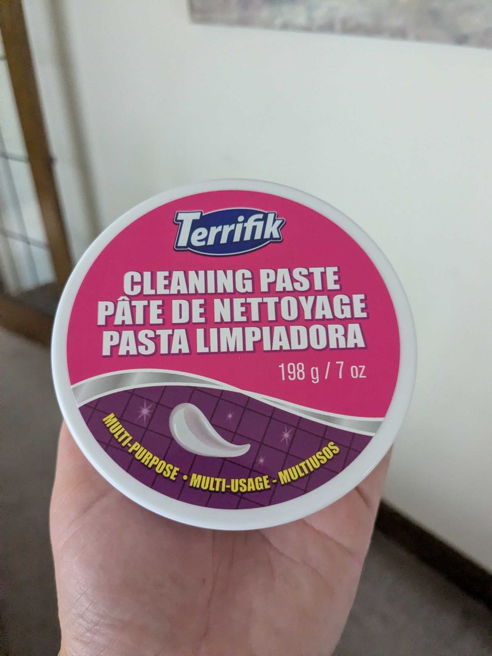 Someone holding a round container of cleaning paste