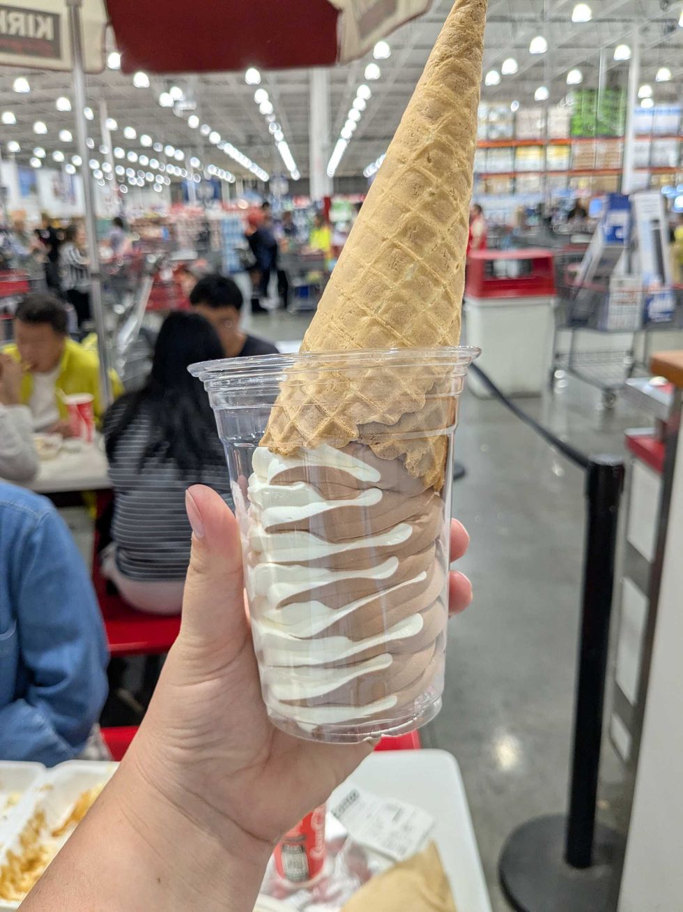 Someone holding an ice cream cone upside down in a plastic cup