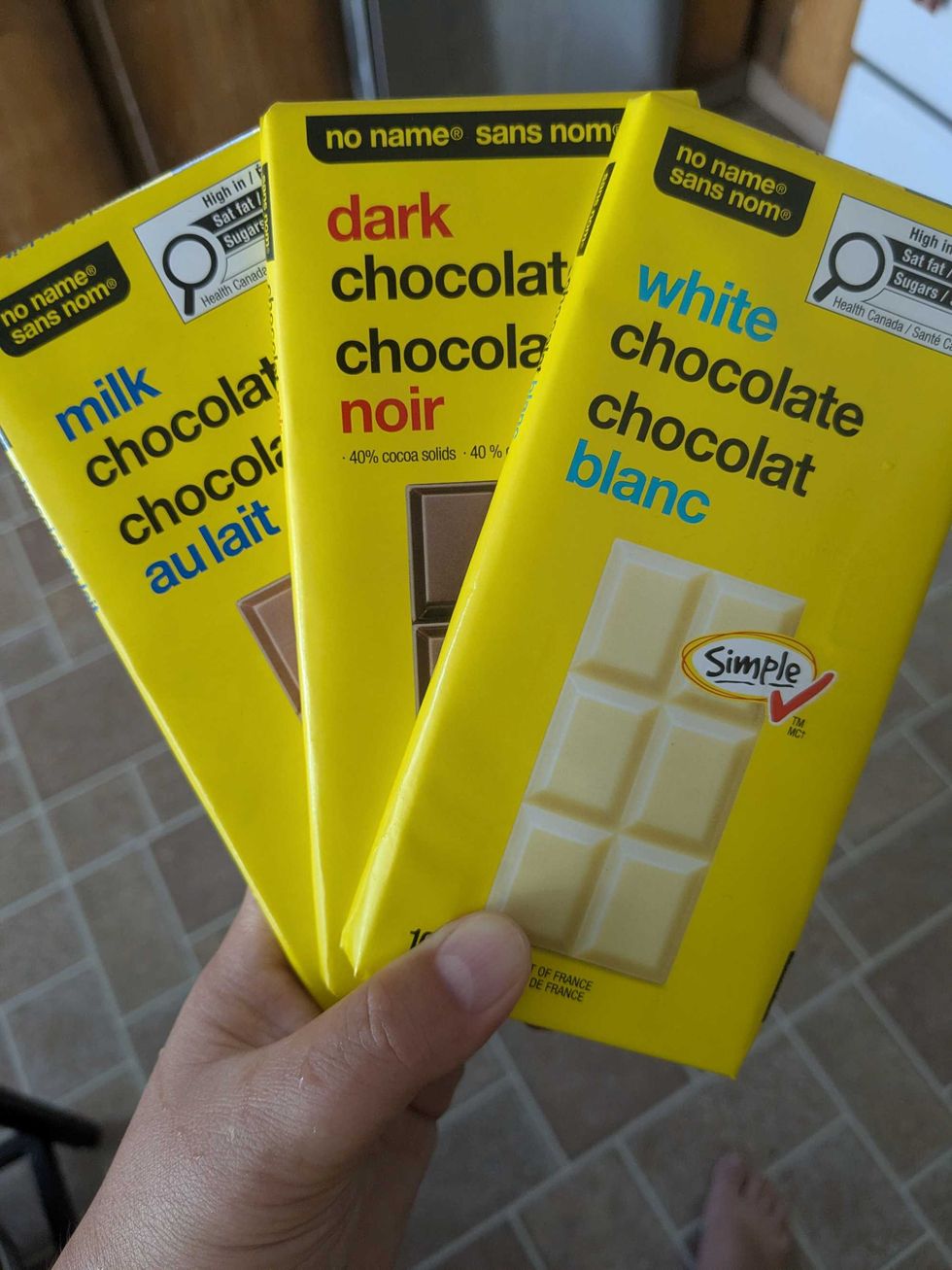 Someone holding three No Name chocolate bars