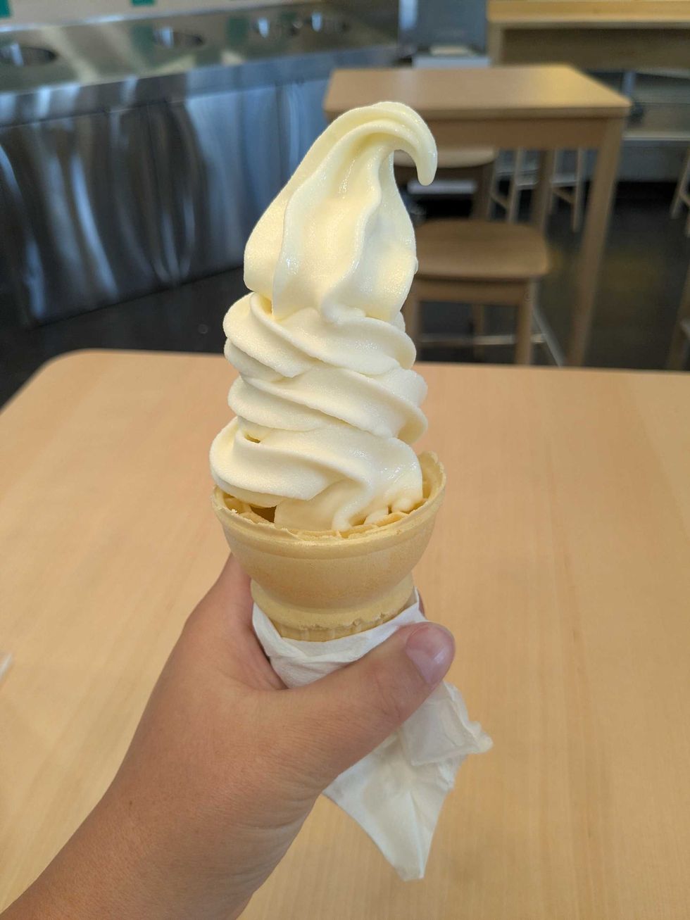Someone holding up a vanilla ice cream cone at IKEA