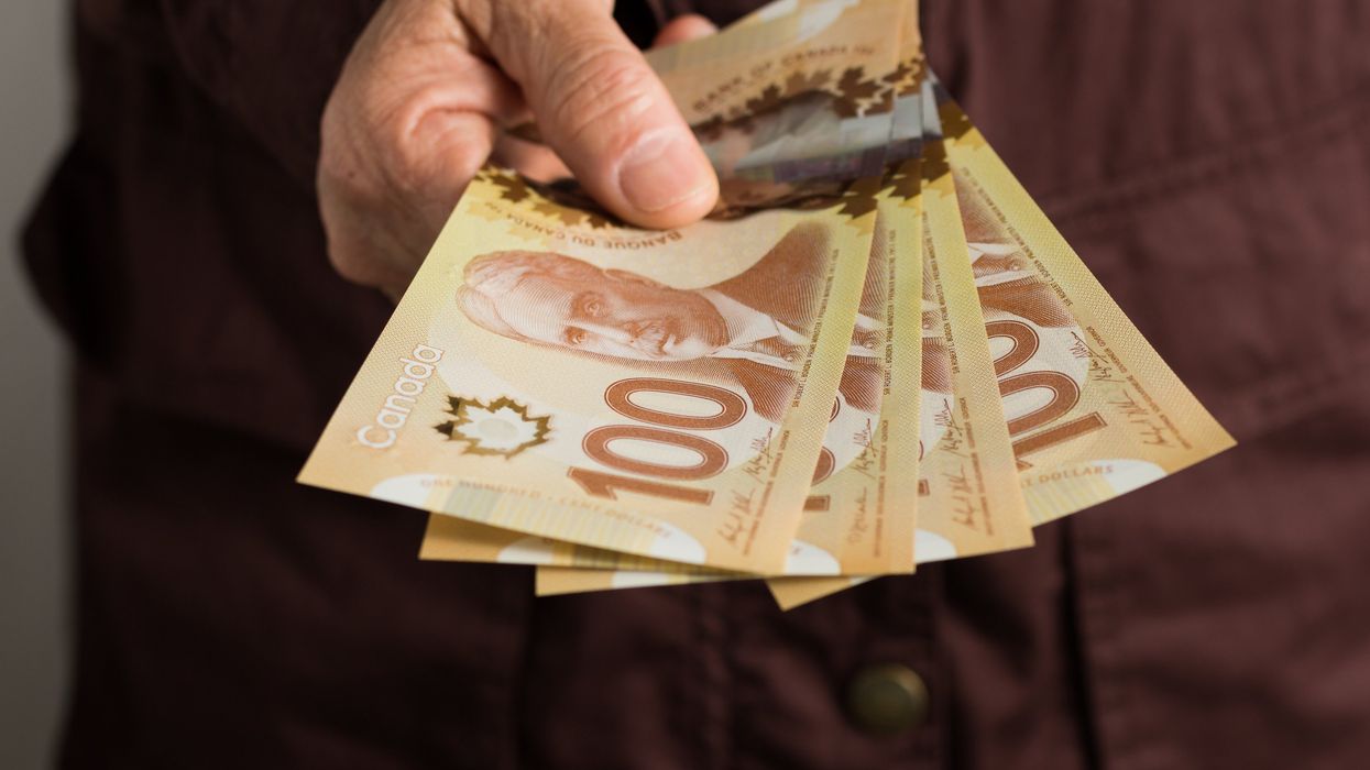 Someone holds out Canadian money.