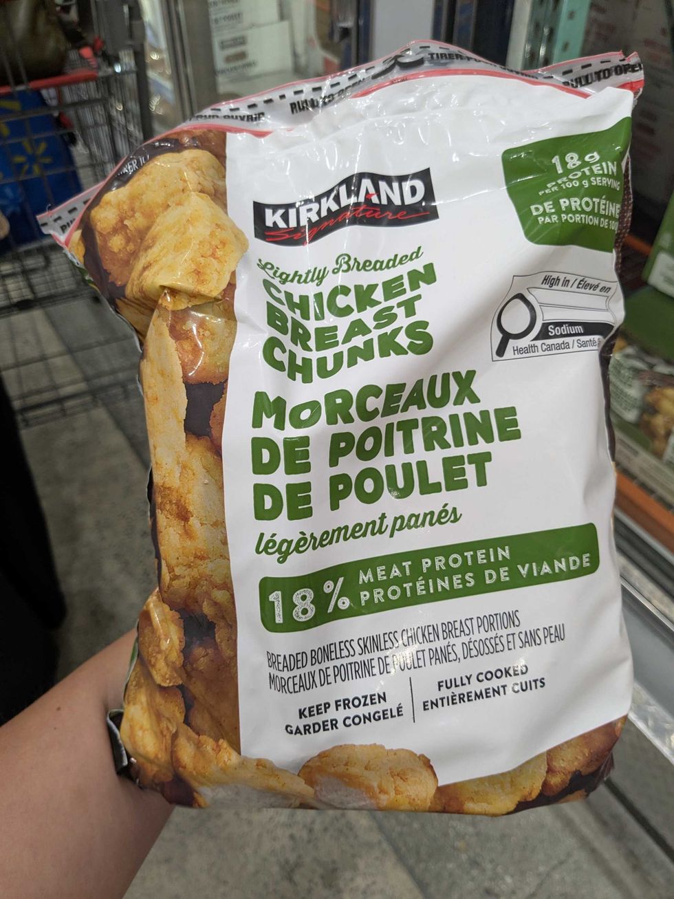 Someone holidng a package of frozen chicken bites