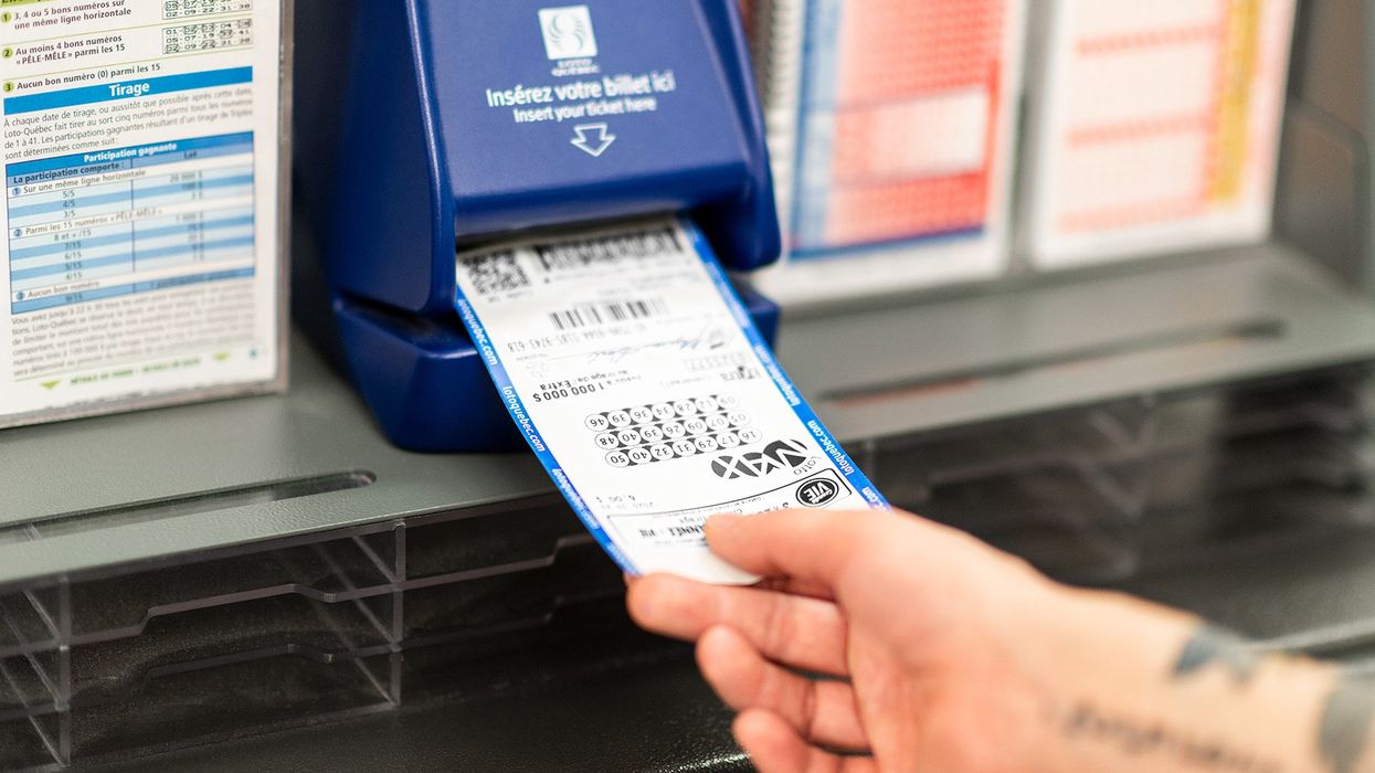 Someone inserting a Lotto Max ticket into a validator machine (illustrative).