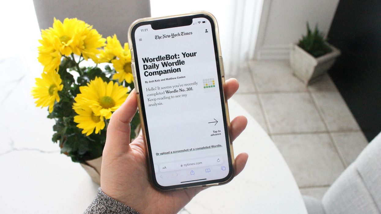 Someone is holding a phone with the new Wordle feature in front of a yellow flowers bouquet.