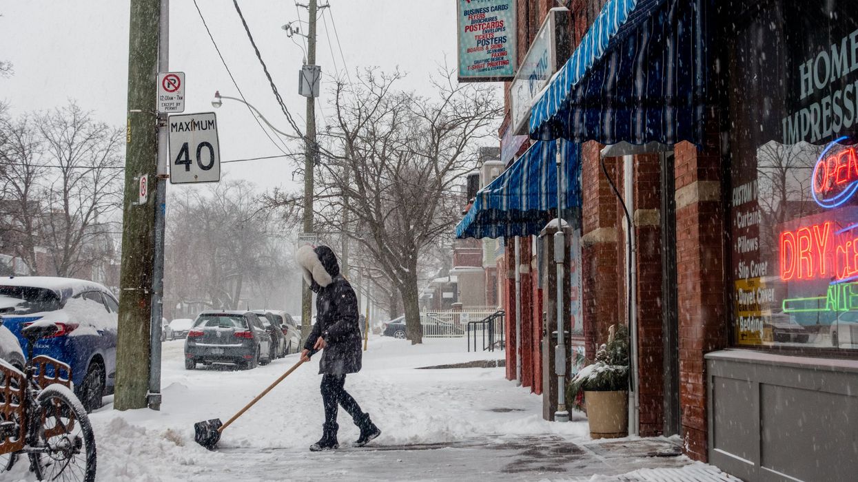 Someone shovelling snow on a Toronto sidewalk.