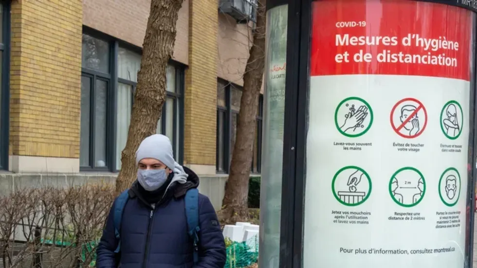 Someone wears a mask in Montreal near a sign showing COVID-19 social distancing and hygiene measures.