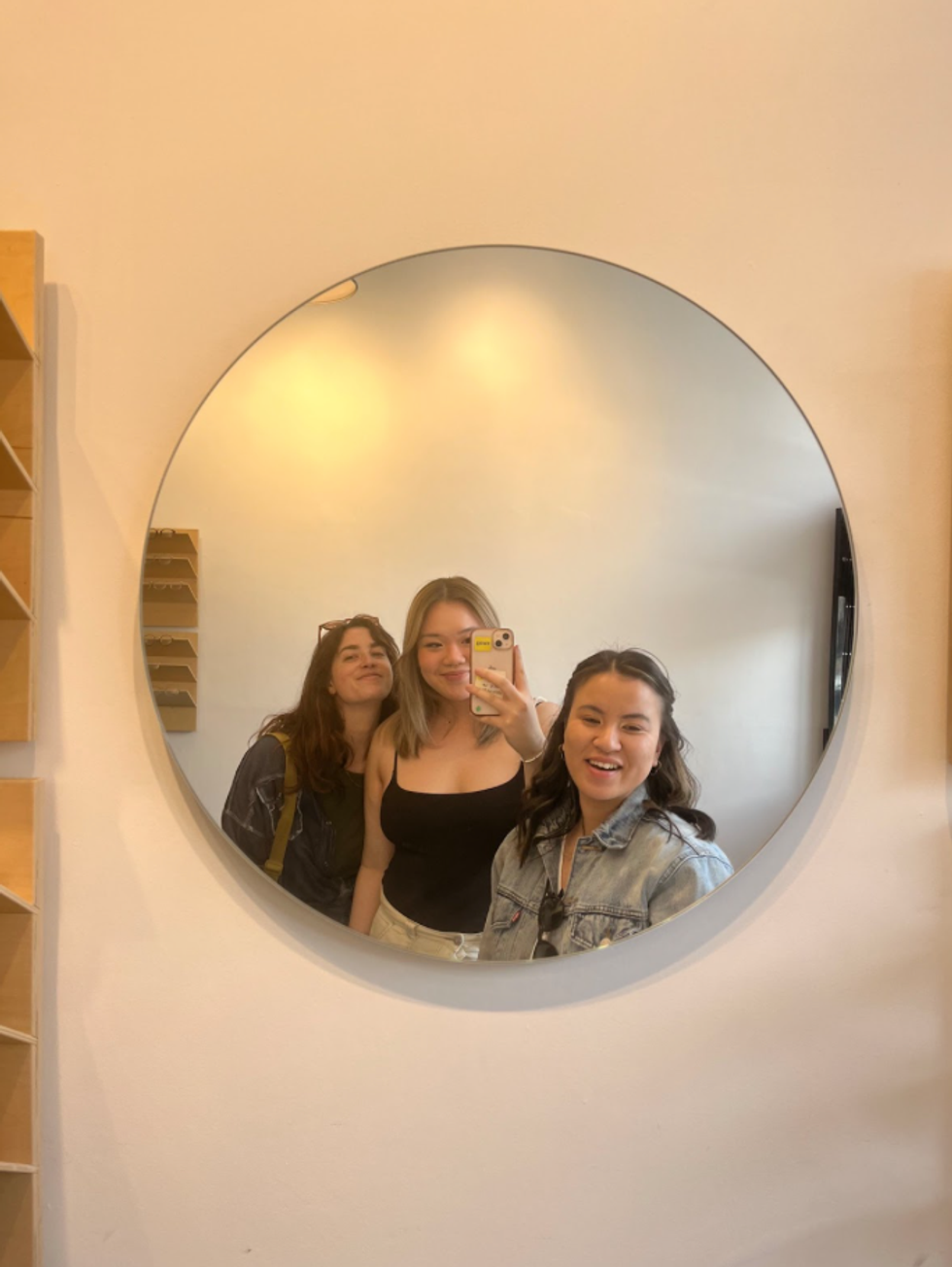 Sophie poses in a mirror with two friends.