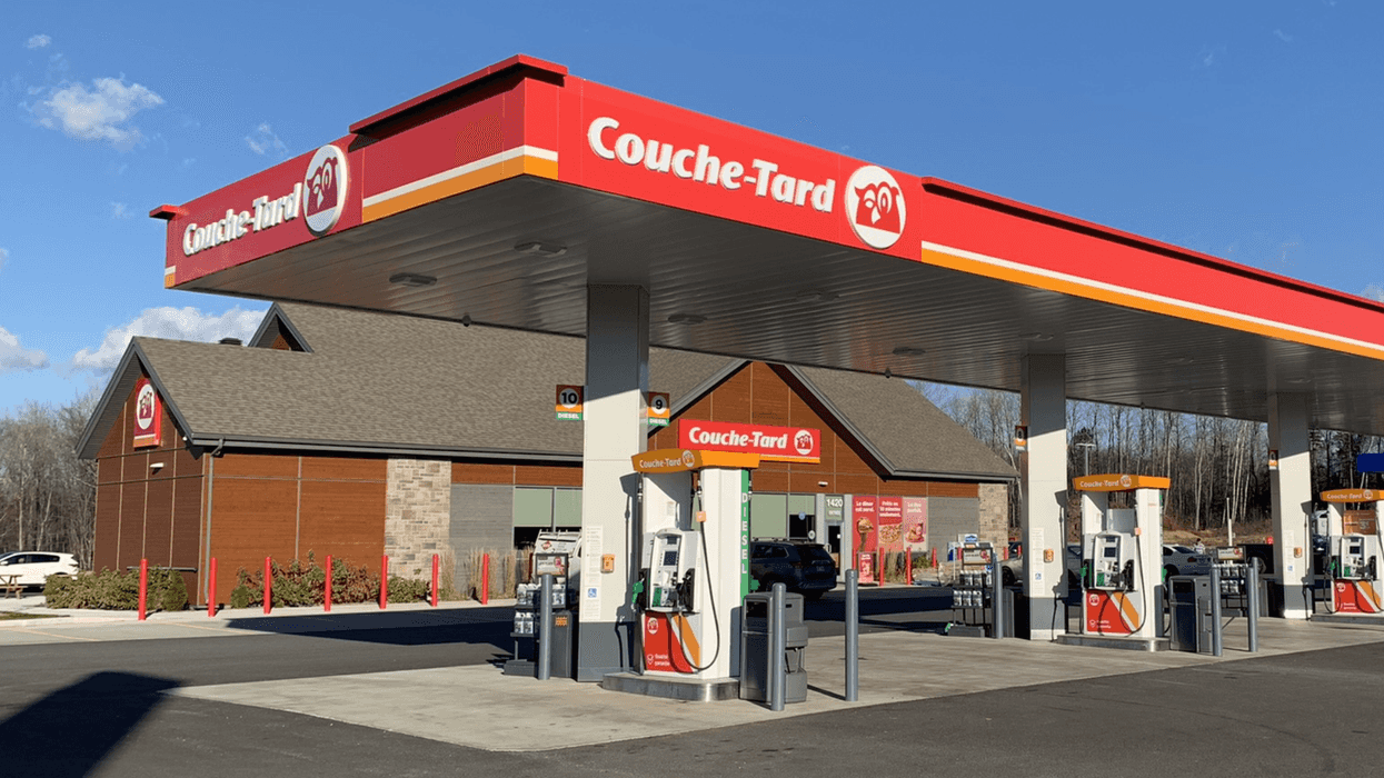 Station-service Couche-Tard moderne avec plusieurs pompes à essence et dépanneur sous un ciel bleu.