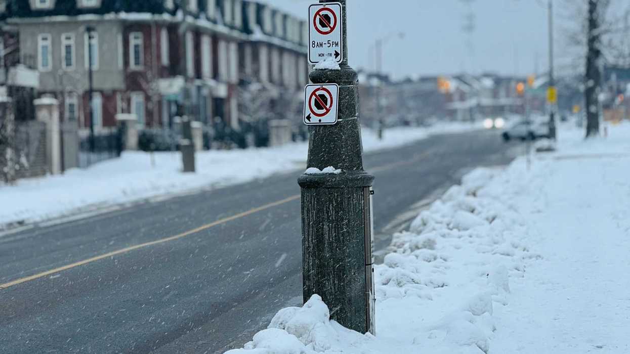 street in ontario during snowfall with a no parking sign