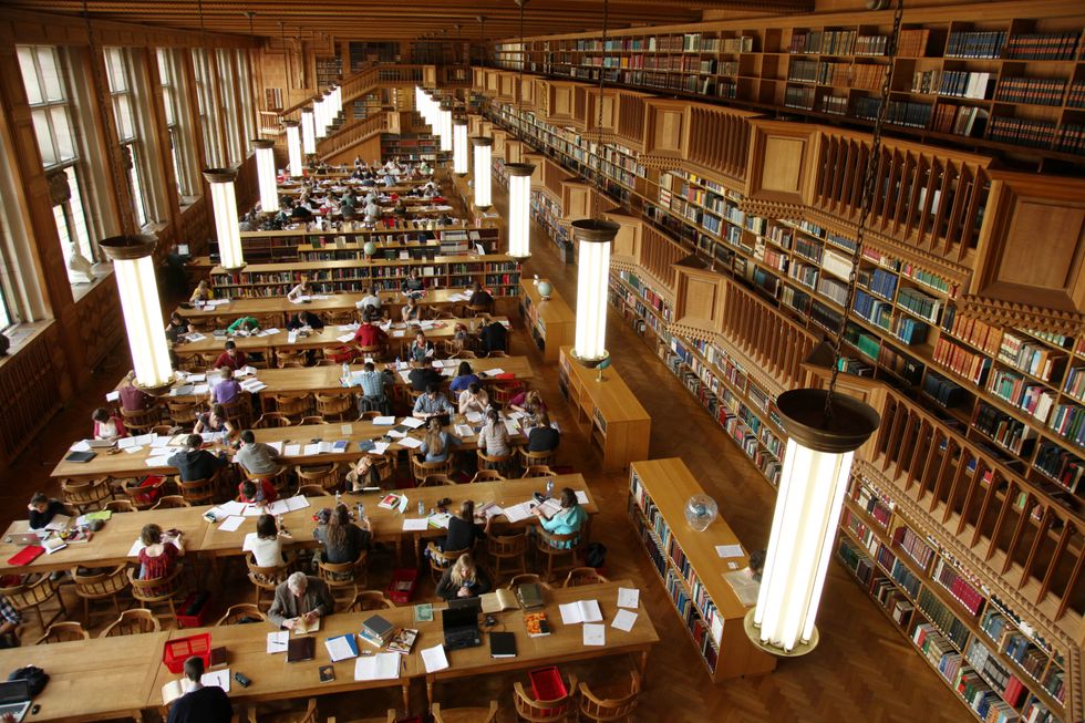 Students sitting at a tables studying in a university library..