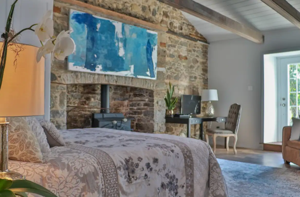 Suite priv\u00e9e avec un grand lit, un foyer et un mur de pierre.