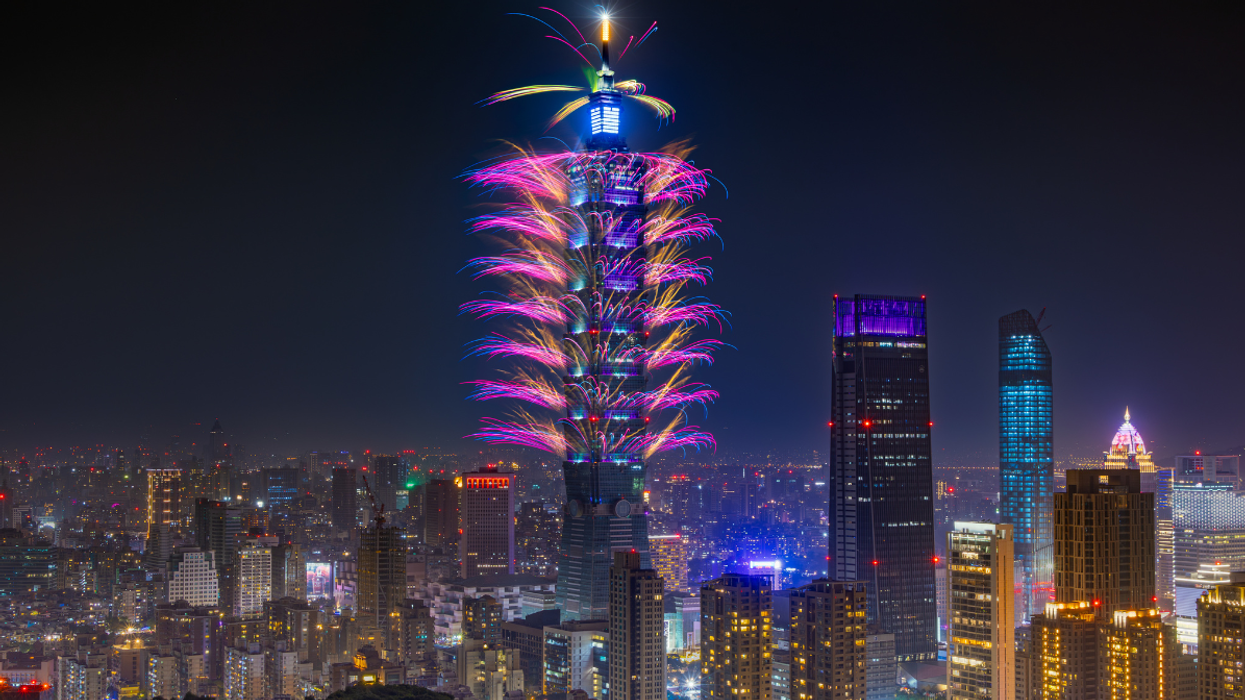 Taipei 101 lit up with fireworks during a night celebration, with the city skyline glowing below.