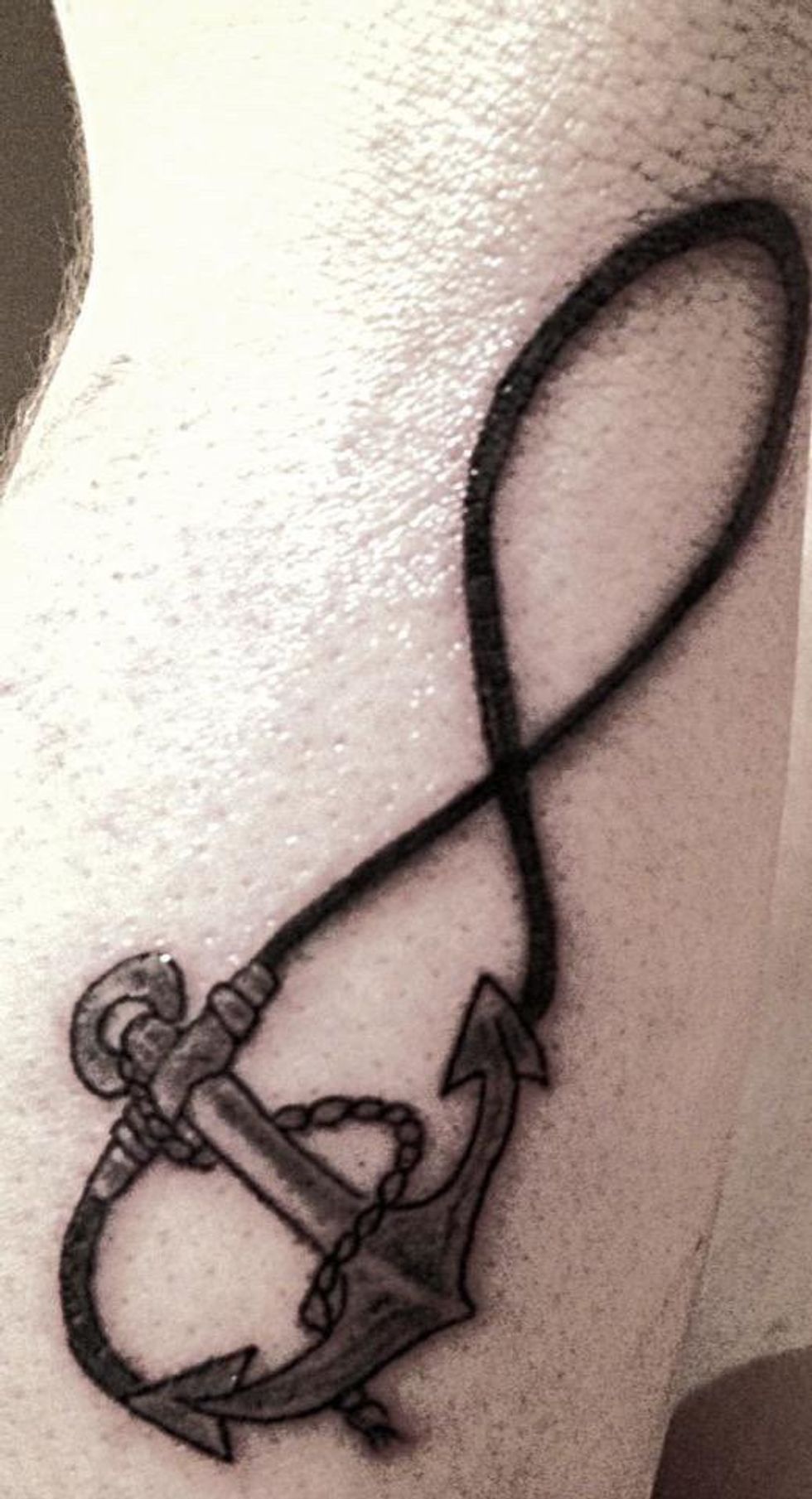 Tatouage d'un symbole infini et d'un ancre \u00e0 bateau en noir et gris.