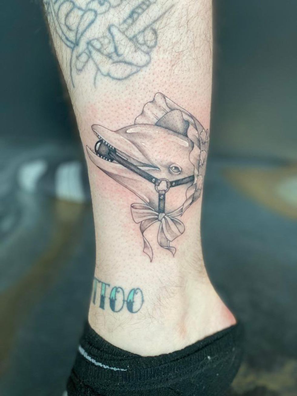 Tattoo d'une t\u00eate de dauphin BDSM avec un bonet sur la jambe