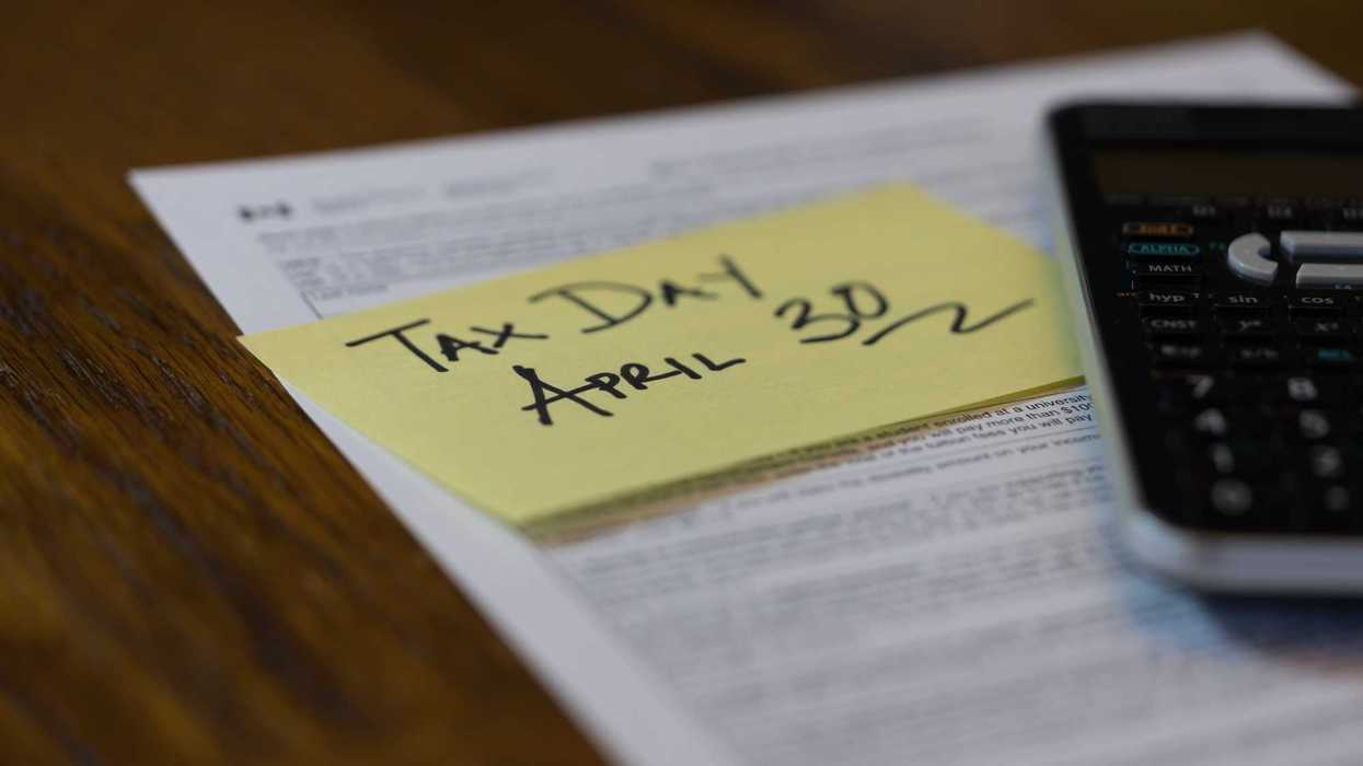 tax forms with a tax day sticker and a calculator