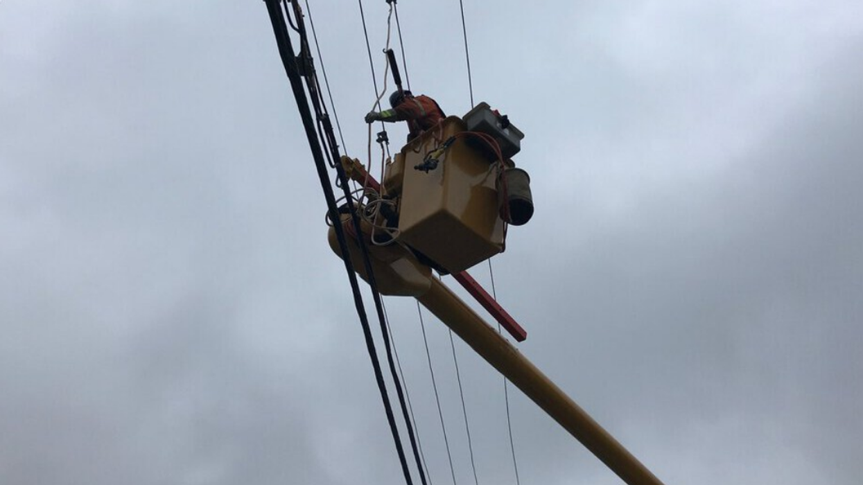Technicien d'Hydro-Québec travaillant sur des fils électriques à partir d'une nacelle.