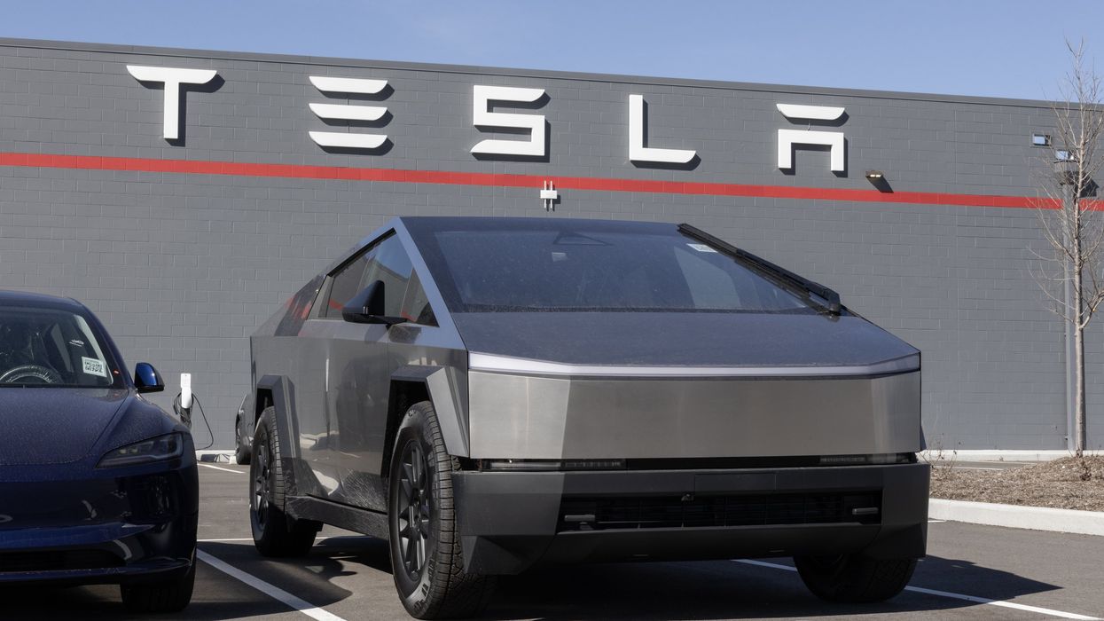 Tesla Cybertruck parked in front of a Tesla dealership.
