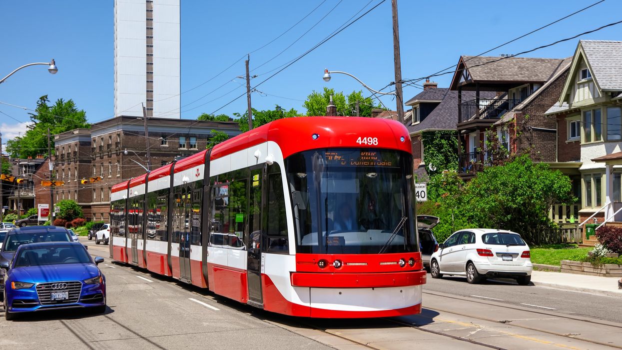 The 504 King streetcar moving alongside traffic on a sunny day in Toronto.
