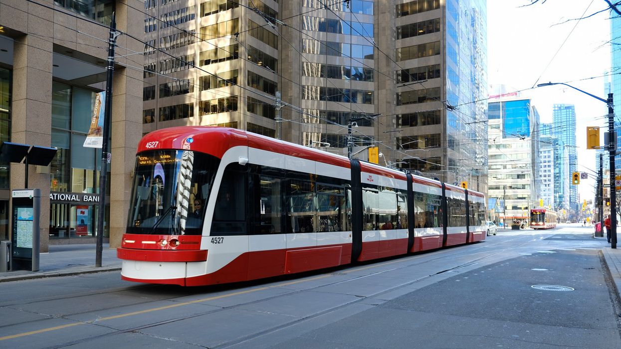 The 504 TTC streetcar going down King St. surrounded by large buildings.