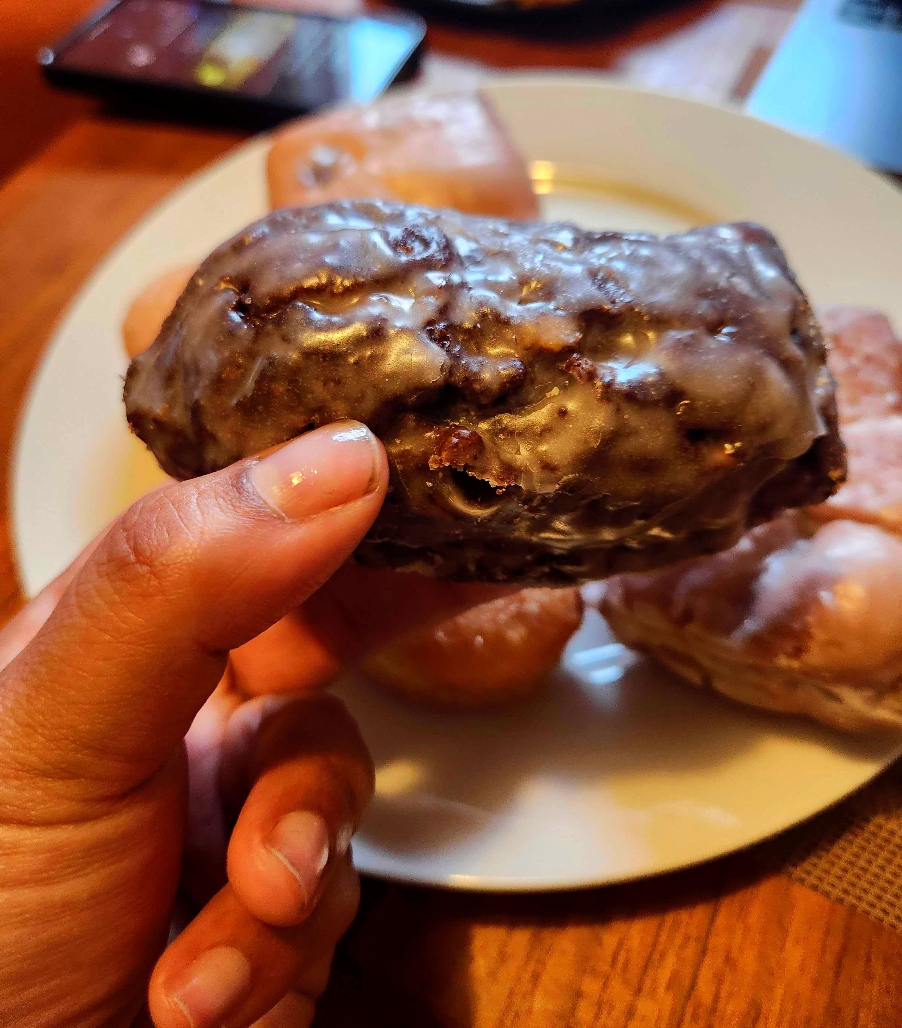 The author holds a glazed chocolatey donut.