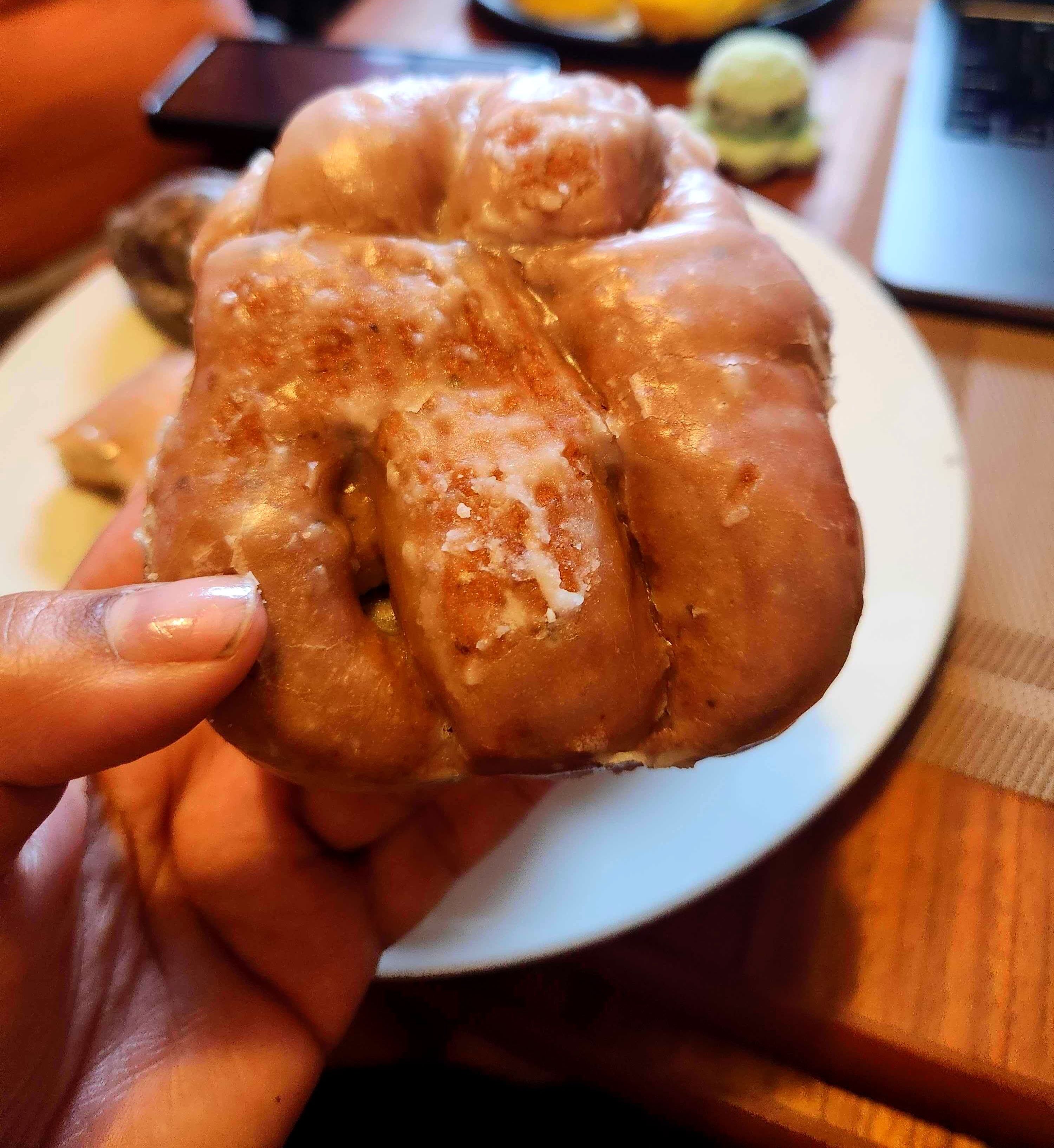 The author holds a glazed fritter-style donut.