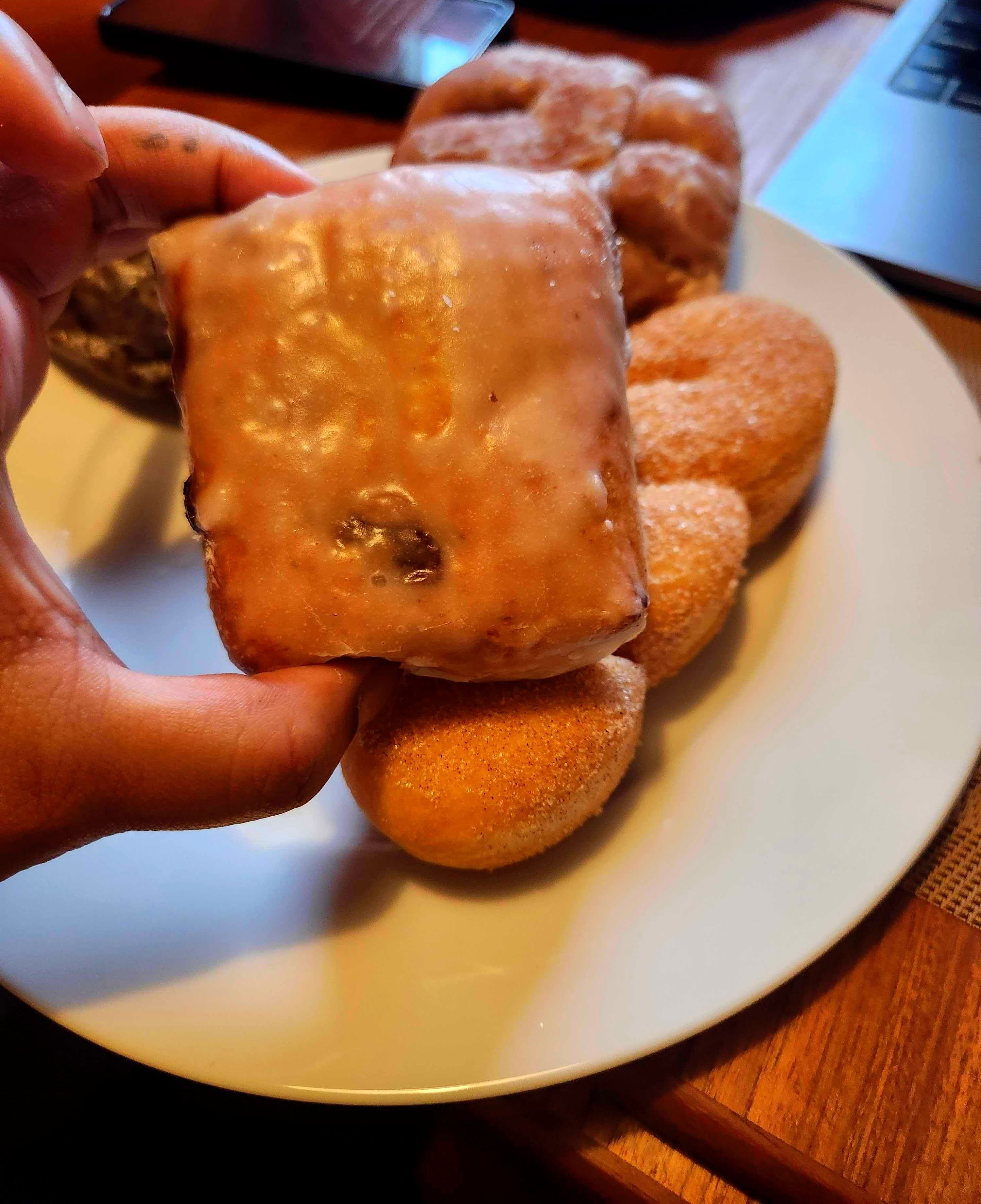 The author holds a glazed square donut with raisins.