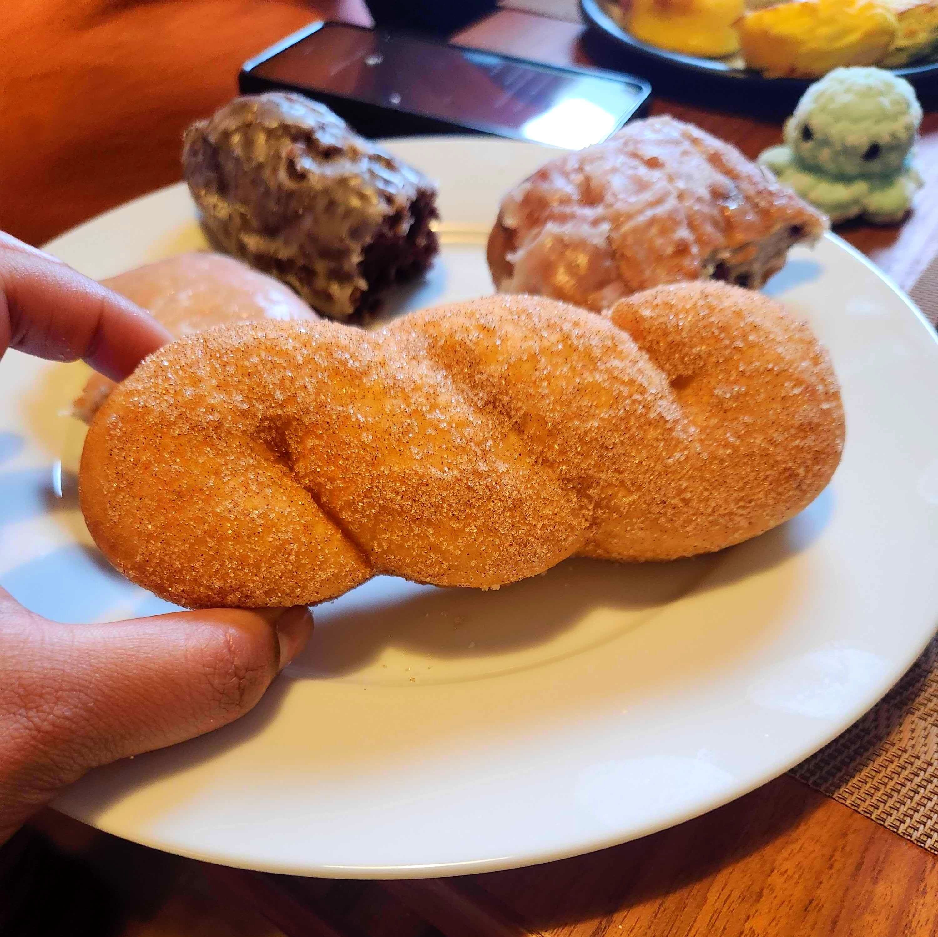 The author holds a sugar-covered twisted donut.