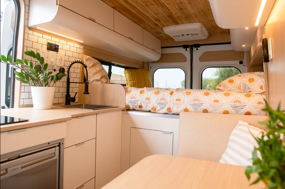 The bed and kitchenette inside of a tiny home on wheels.