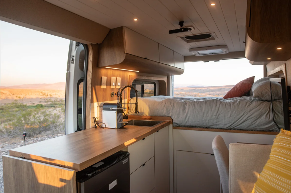 The bed and kitchenette inside of a tiny home on wheels.