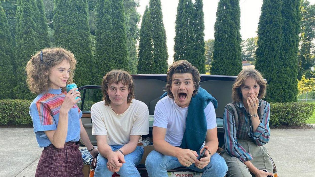 The cast of 'Stranger Things' sitting on a car.